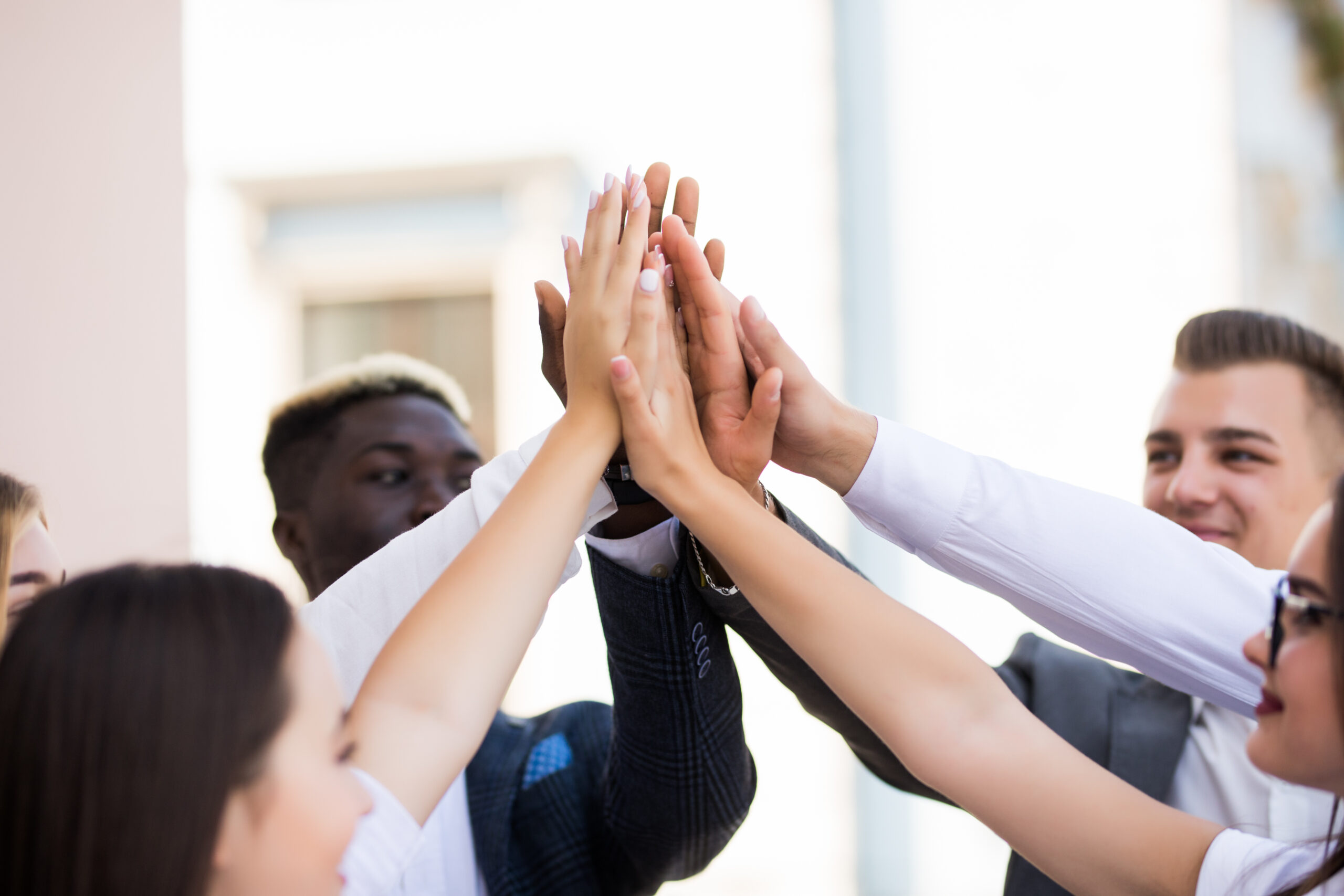 Happy successful multiracial business team giving a high fives gesture as they laugh and cheer their success Happy multiracial business team giving a high fives gesture as they laugh and cheer their success