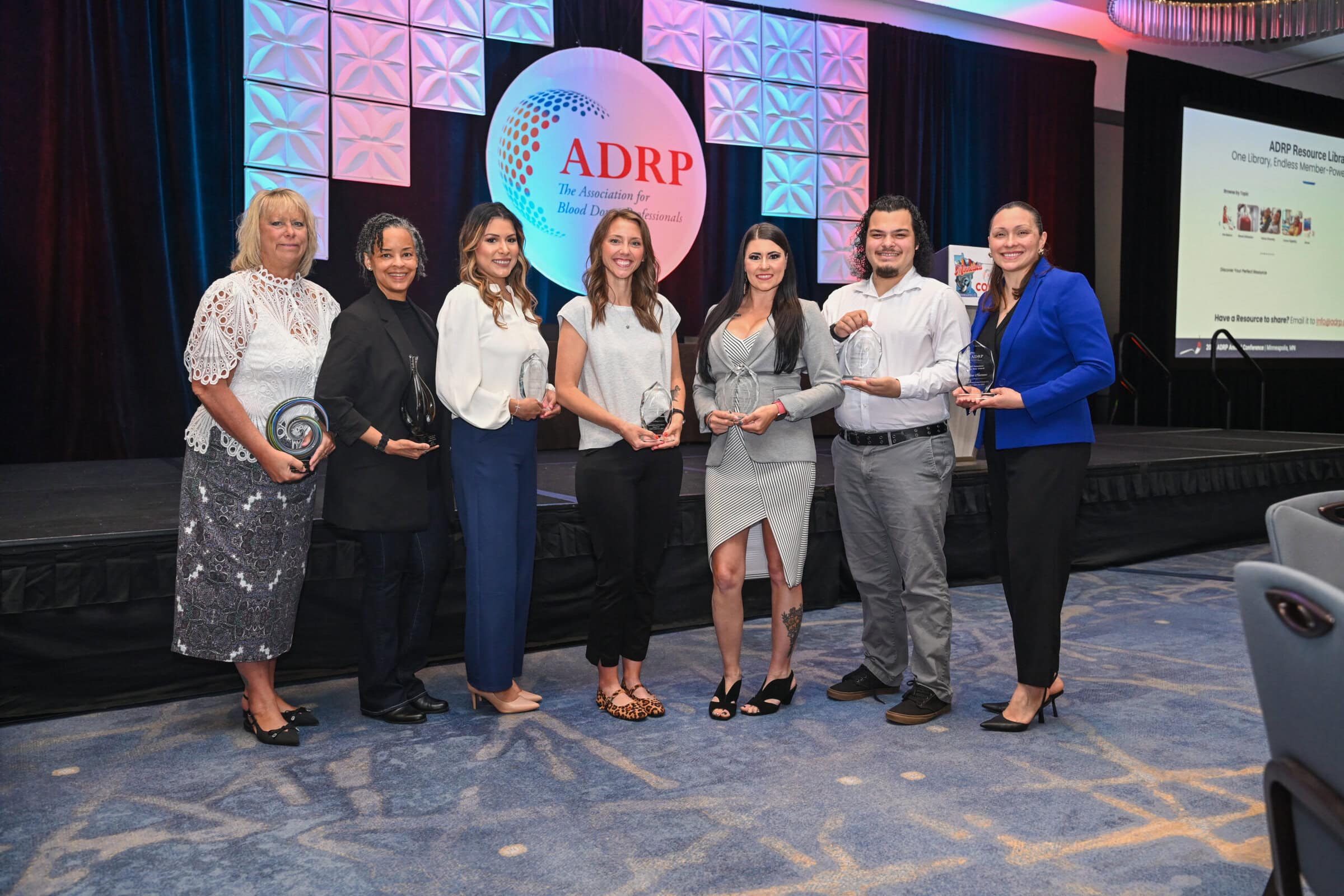 Group of people holding their awards in front of the ADRP logo at the ADRP Annual Conference